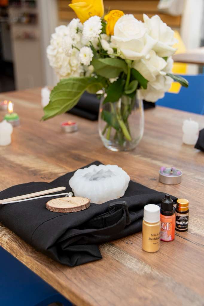 A poured white candle beside fragrance oils, mica pigment and a fresh wick
